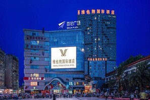 Et hotel med tydelig skiltning for Vienna International Hotel, omgivet af moderne bygninger og livlig gadeaktivitet.