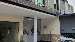 Un edificio moderno con fachada geométrica, amplios ventanales y un espacio exterior cubierto con asientos.