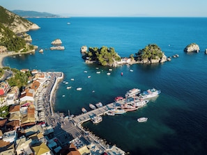 Un pueblo costero con un puerto deportivo, barcos y un paisaje montañoso.