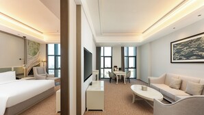 A hotel room with a bed, a desk, a sofa, a dining table, and a large window. - Holiday Inn Jianhu (Yancheng)