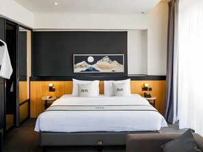 Ein Hotelzimmer mit Bett, Nachttischen, einem Wandbild und einem Beistelltisch.
