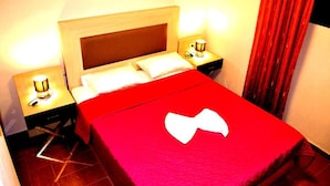 Una habitación de hotel con cama, mesitas de noche y colcha roja.