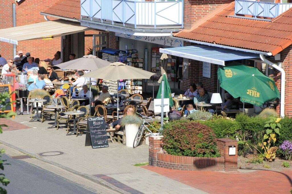 Ein Straßencafé mit Tischen, Stühlen, einem Schild und einer Ziegelwand.
