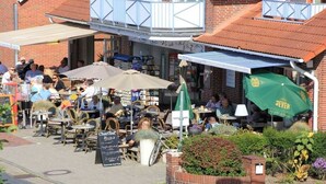 Ein Straßencafé mit Tischen, Stühlen, einem Schild und einer Ziegelwand.