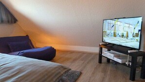 Ein Zimmer mit einem Bett, einem Fernseher auf einem Schrank und einem Fenster.