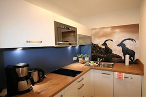 A kitchen with a coffee maker, a microwave, and a sink. - Alpenflair Holiday Apartment 107 (Oberstdorf)