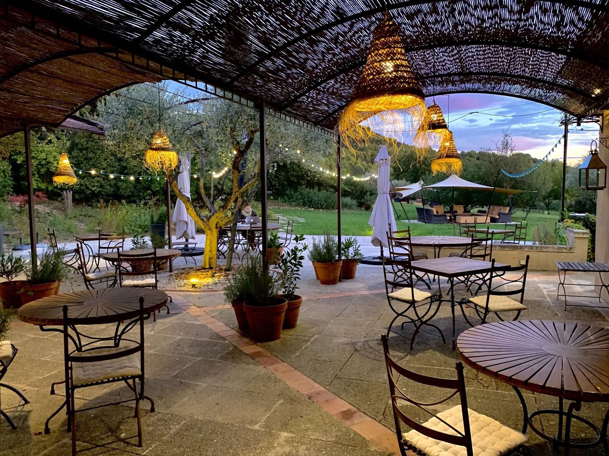 An outdoor patio area with tables and chairs, string lights, and a view of the surrounding landscape.