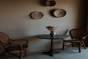 A room with a round table, two wicker chairs, and three woven baskets on the wall. - Hotel Auberge La Feniere (Cadenet)
