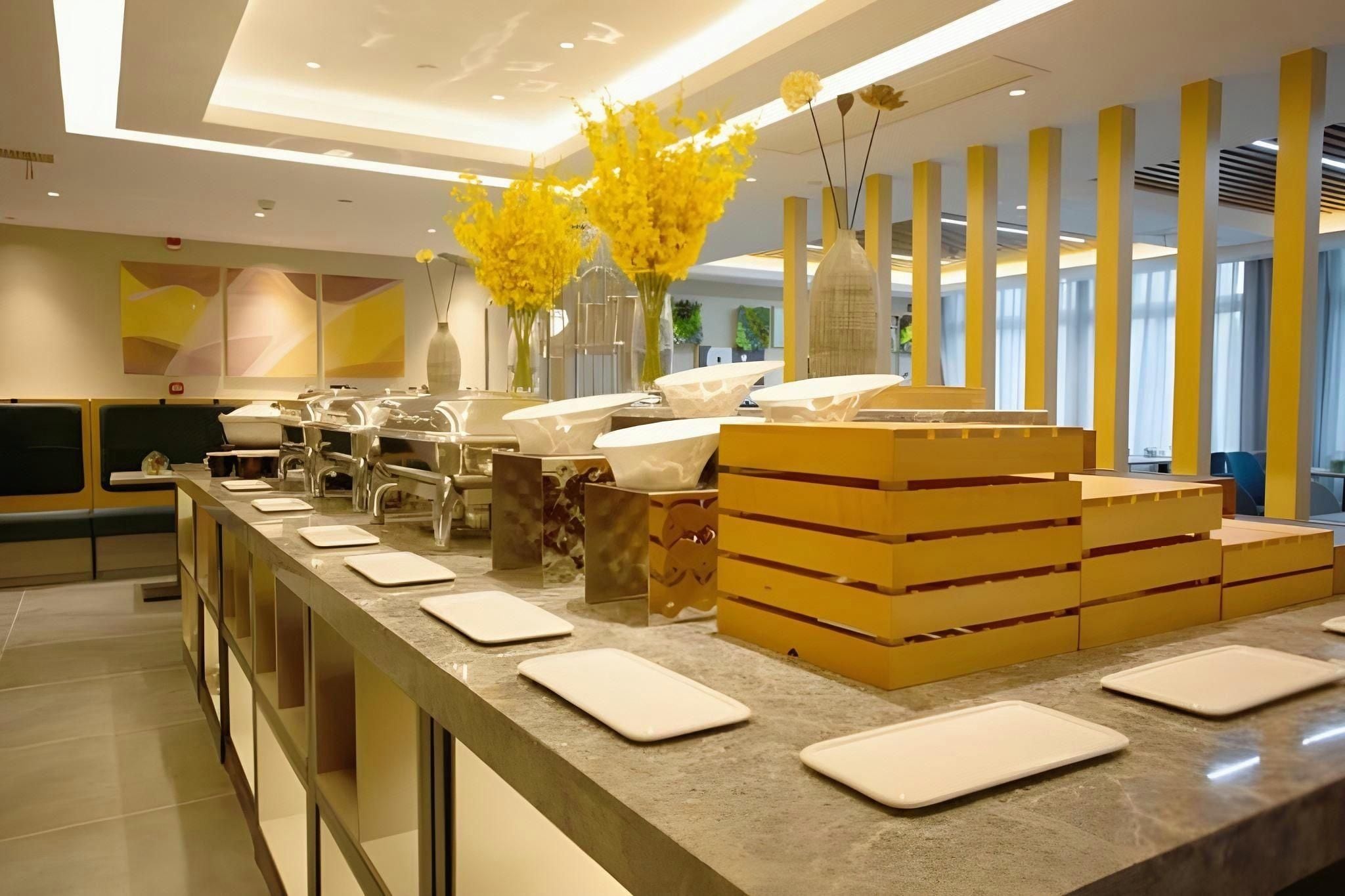 A modern hotel reception area with a marble counter, seating, and decorative vases.