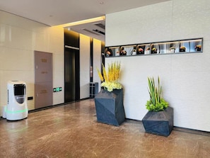 A modern lobby with a reception area, a self-service kiosk, and a wall-mounted display of flowers. - Homeinn Selected (Xuzhou)