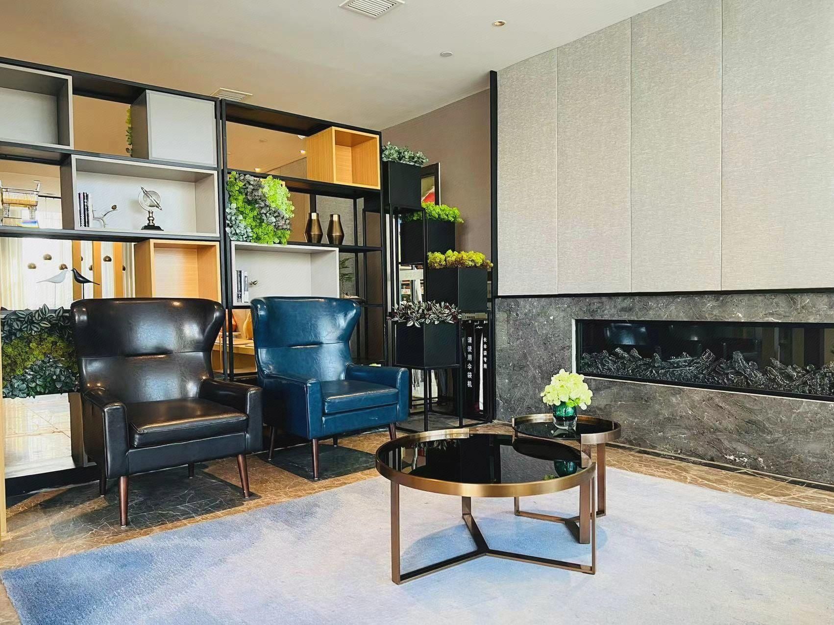 A modern living room with a fireplace, two leather armchairs, a blue sofa, and a coffee table.