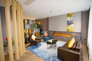 A modern living room with a fireplace, leather sofas, a blue armchair, and a bookshelf. - Homeinn Selected (Xuzhou)