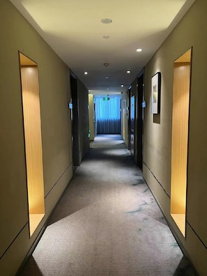 A hotel hallway with carpeted floors, recessed lighting, and framed pictures on the walls. - Homeinn Selected (Xuzhou)