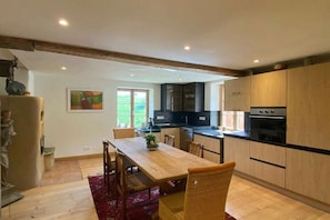 A modern kitchen with wooden cabinets, a dining table, and chairs.
