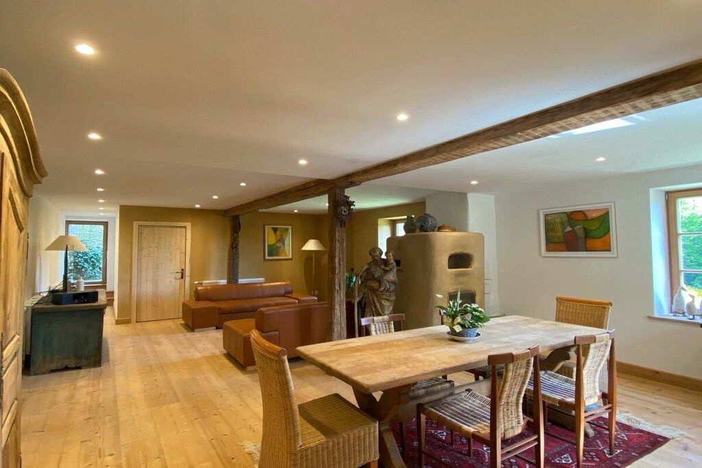 A dining area with a wooden table and wicker chairs, a sofa, and a fireplace.