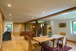 A dining area with a wooden table and wicker chairs, a sofa, and a fireplace.