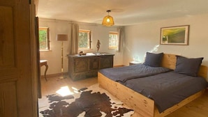 A bedroom with a wooden bed, a cowhide rug, a dresser, and a hanging light fixture.