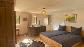 Un dormitorio con una cama de madera, un tapete de cuero de vaca, un aparador y una lámpara colgante.