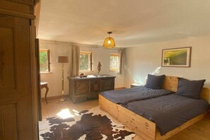 Ein Schlafzimmer mit einem hölzernen Bett, einem Kuhfellteppich, einem Schminktisch und einer Pendelleuchte.