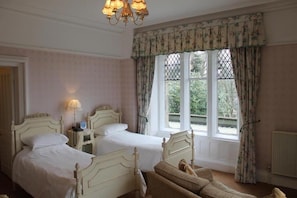 A room with two beds, a chandelier, and a window with curtains. - The Oakwood Hall Hotel (Bingley)