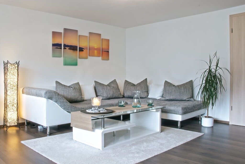 A modern living room with a sofa set, a glass coffee table, and a potted plant.
