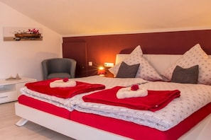 Quarto de hotel com cama, cadeira, mesa de cabeceira e quadro na parede.