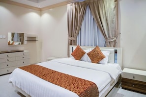 A modern hotel room with a large bed, a bedside table, a dresser, and a mirror. - OYO 628 Wasan Suites (Riyadh)