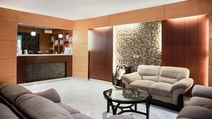 En moderne lobby med reception, siddeområde og en dekorativ væg.