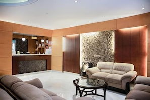 A modern lobby with a reception desk, seating area, and a decorative wall. - OYO 628 Wasan Suites (Riyadh)