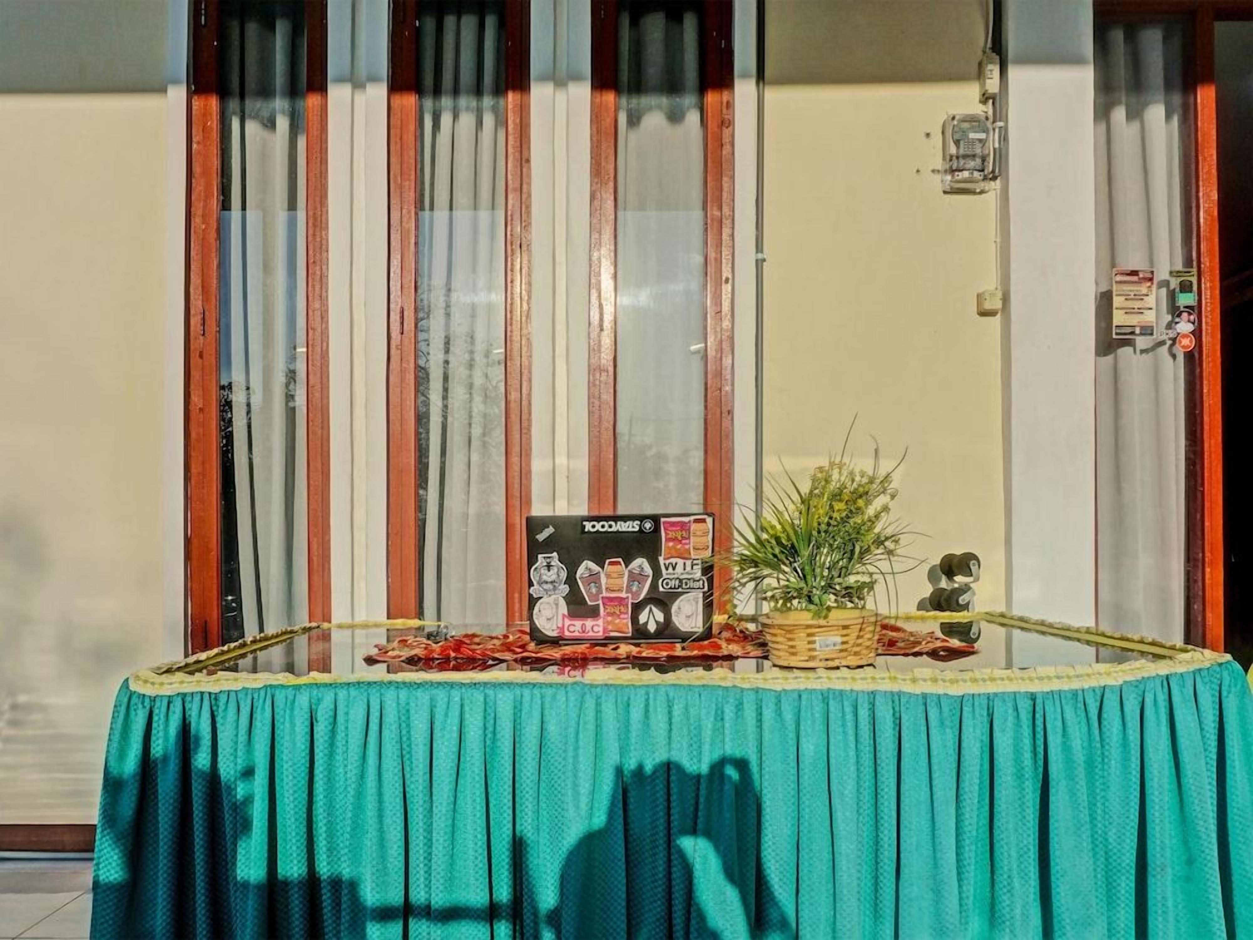 A table with a teal tablecloth, a sign with text, a small plant, and a decorative item.