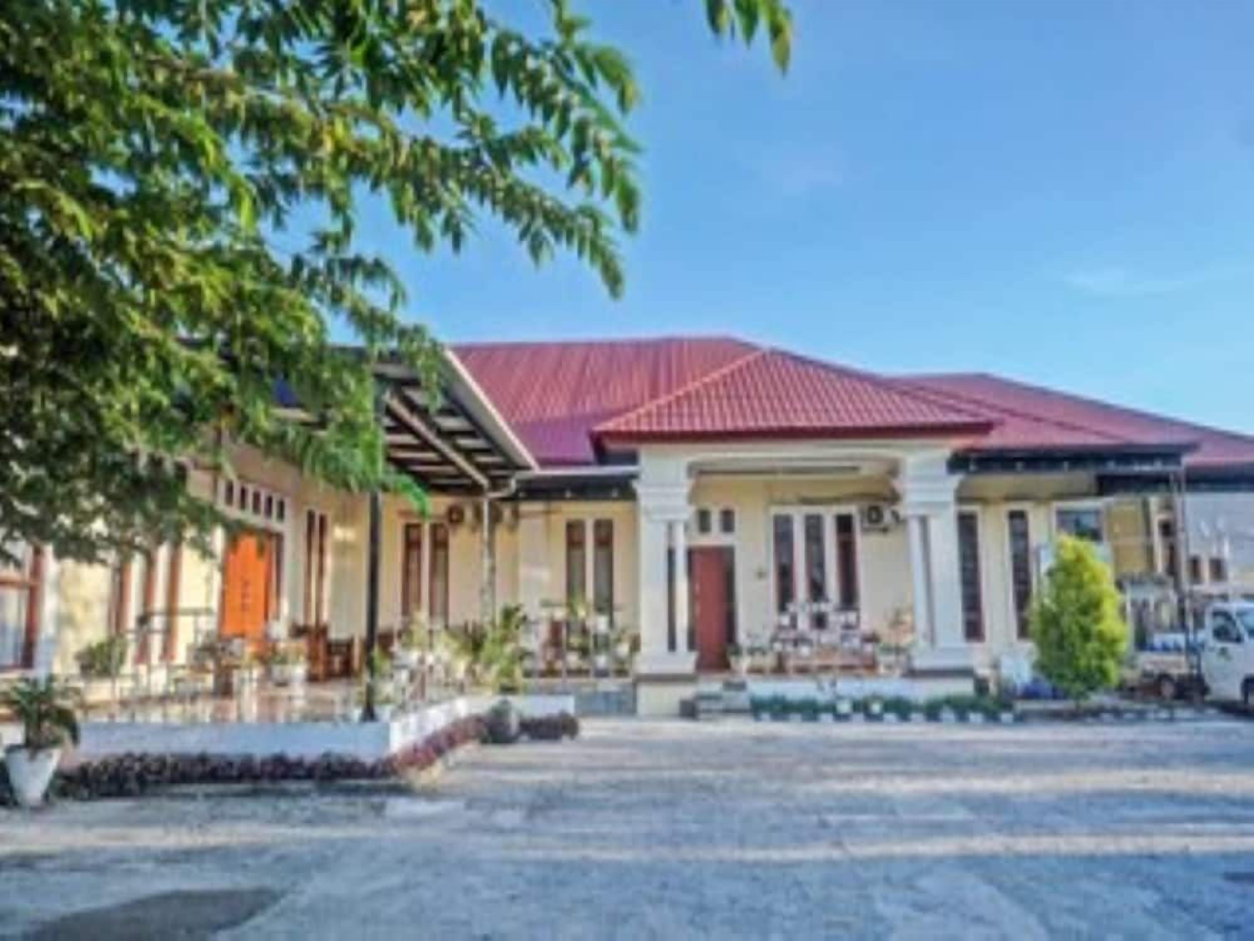 A two-story building with a red roof, a covered outdoor seating area, and a paved driveway.