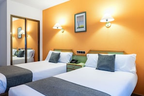 A hotel room with two beds, a nightstand with a phone, and a wall-mounted lamp. - Alda Guijuelo (Guijuelo)