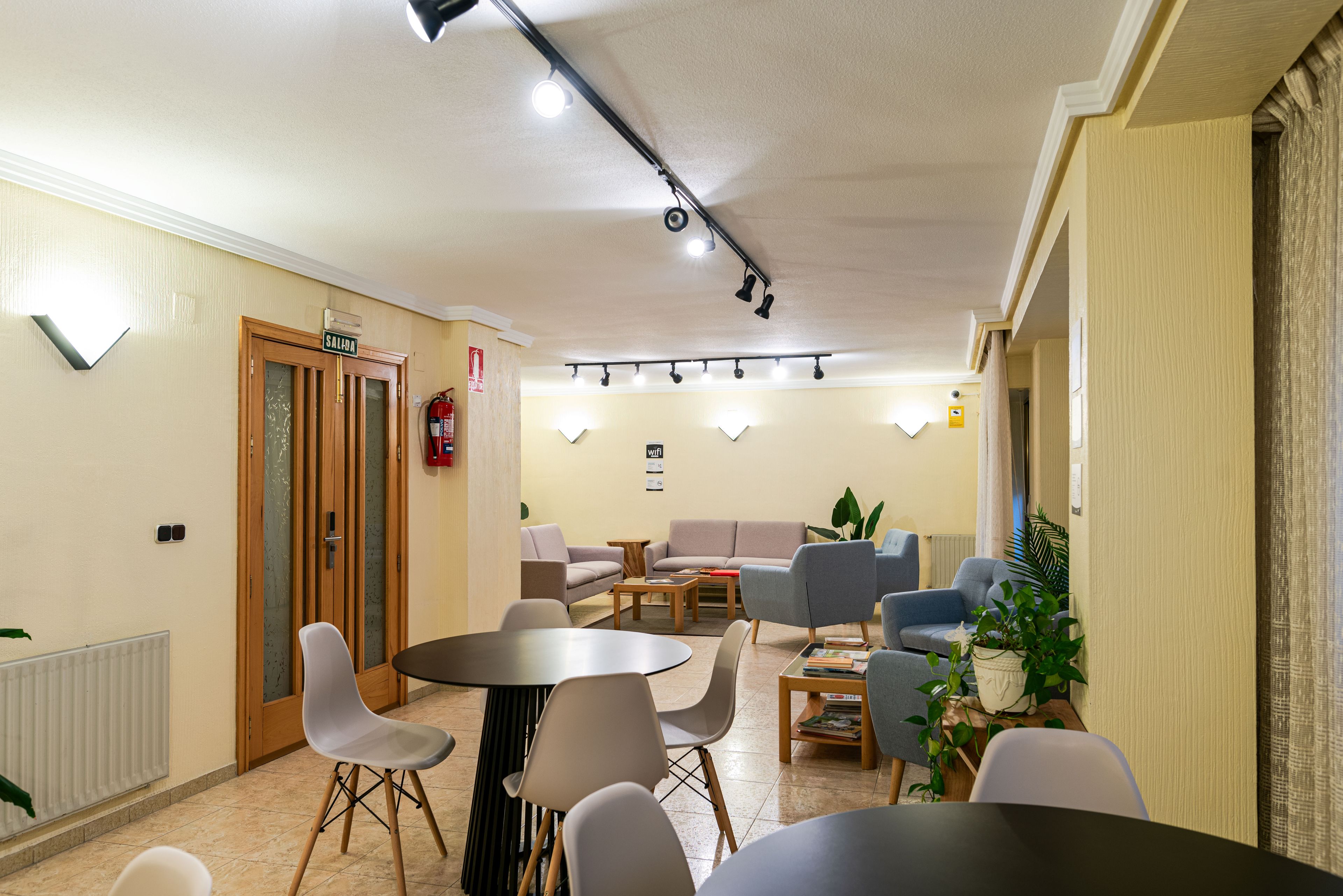 A conference room with a round table, chairs, a sofa, and a fire extinguisher.