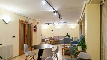 A conference room with a round table, chairs, a sofa, and a fire extinguisher.