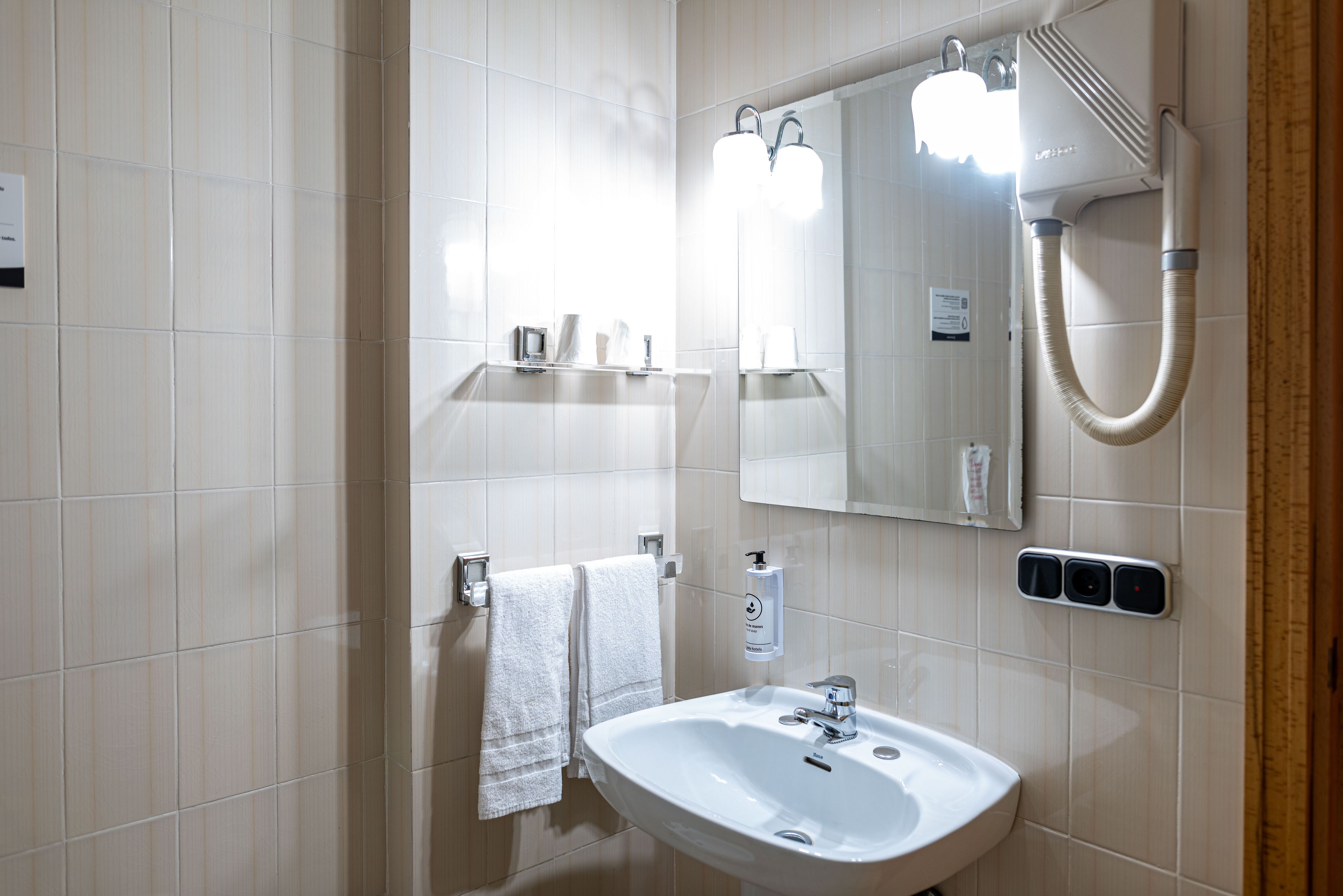 A bathroom with a white sink, a mirror, a towel rack, and a shower.