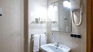 Ein modernes Badezimmer mit einem weißen Waschbecken, zwei Handtuchhaltern, einem Spiegel und einer Duschbrause.