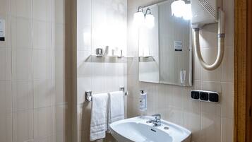 A bathroom with a white sink, a mirror, a towel rack, and a shower.