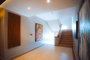 A hallway with a wooden door, a staircase, and a painting on the wall. - Elite View Hotel Dakhla (Dakhla)