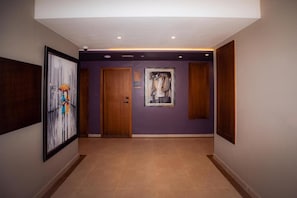 A hallway with a wooden door, a framed abstract painting, and a wall-mounted picture. - Elite View Hotel Dakhla (Dakhla)