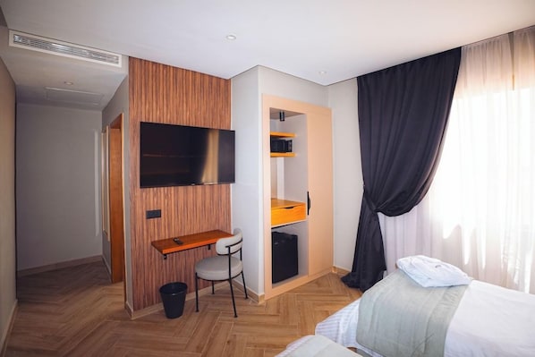 A hotel room with a bed, a desk with a chair, a television mounted on the wall, and a wardrobe with shelves. - Elite View Hotel Dakhla (Dakhla)