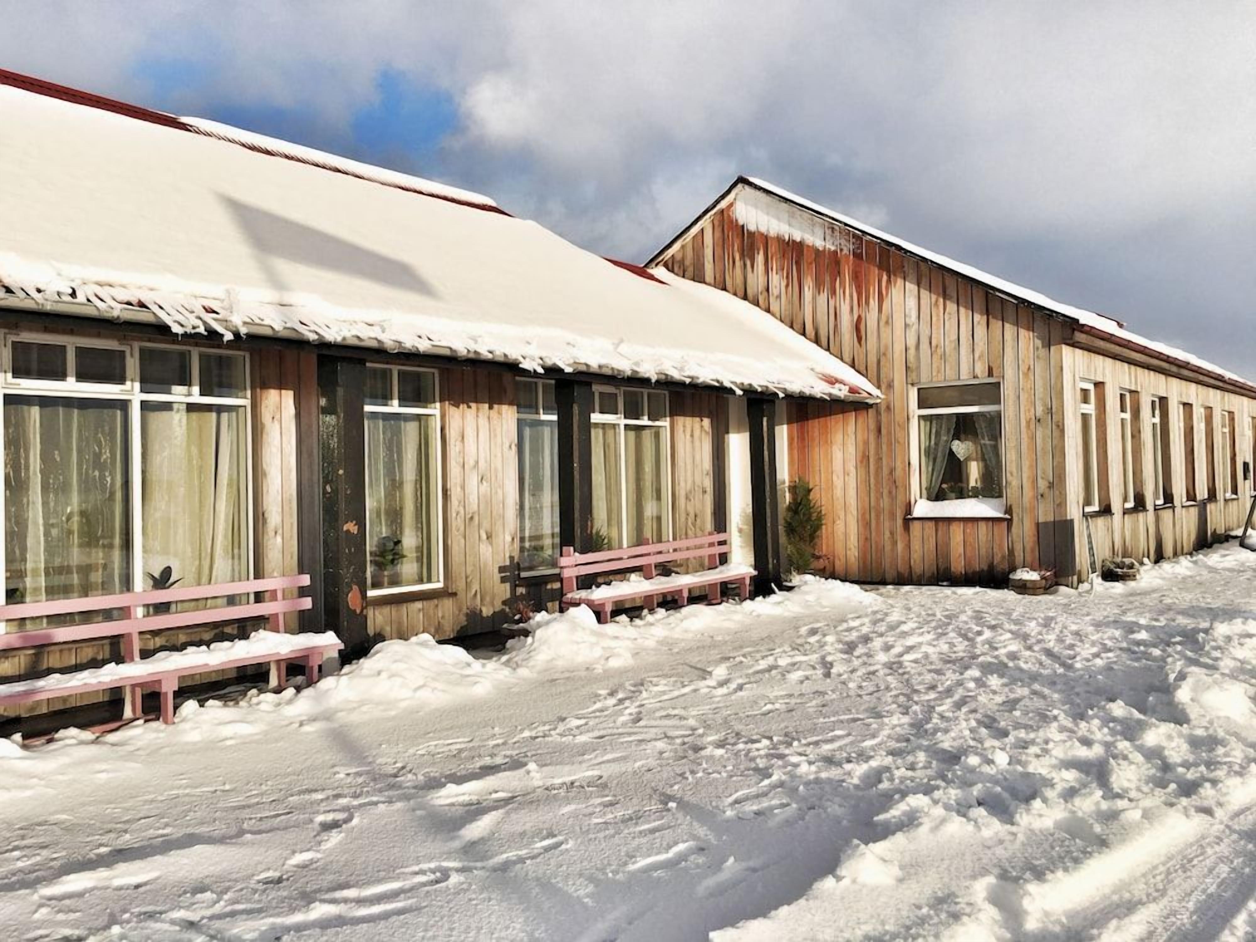 Ein Holzhaus mit verschneitem Dach und Fenstern.