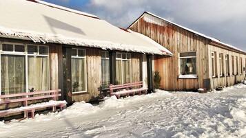 A wooden building with a snow-covered roof and windows.