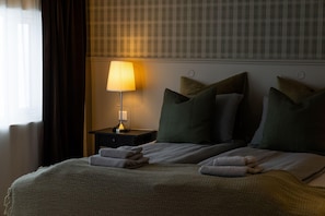 A hotel room with a bed, pillows, a nightstand with a lamp, and a window with curtains. - Hótel Rjúkandi (Eyja- og Miklaholtshreppur)