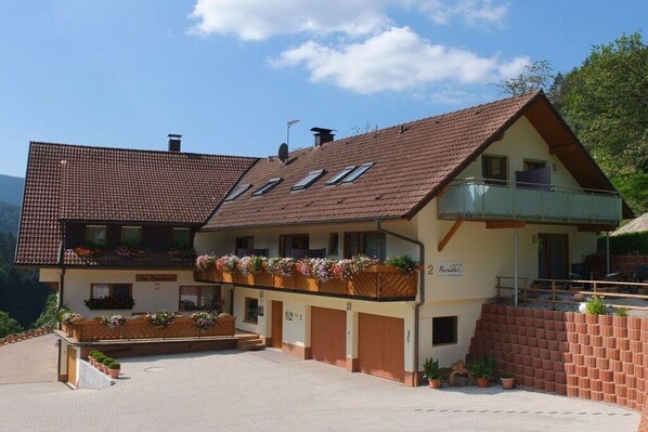 Ein zweistöckiges Gebäude mit geneigtem Dach, einem Balkon im oberen Geschoss und einem Schild, das ein Restaurant anzeigt.