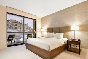 Camera d'albergo moderna con un letto grande, due comodini, una sedia e vista all'esterno.