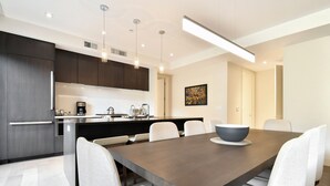 Una cocina moderna con armarios oscuros, una isla central y una zona de comedor con una mesa grande y sillas.