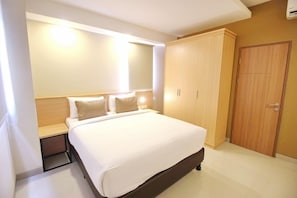 Habitación de hotel con cama, mesita de noche, armario y lámpara fijada a la pared.