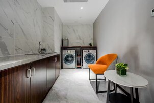 Cocina compacta con salpicadero de mármol, lavadora y una pequeña zona de comedor con mesa y silla.