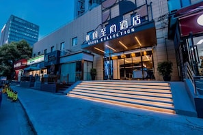 A hotel entrance with a modern facade, a staircase leading to the entrance, and a visible coffee shop on the ground floor. - Yitel Collection Shanghai Hongqiao Gubei Road Yili Road Metro Station (Shanghai)