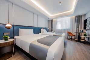 Une chambre d’hôtel avec deux lits, un bureau, une chaise et une petite table.